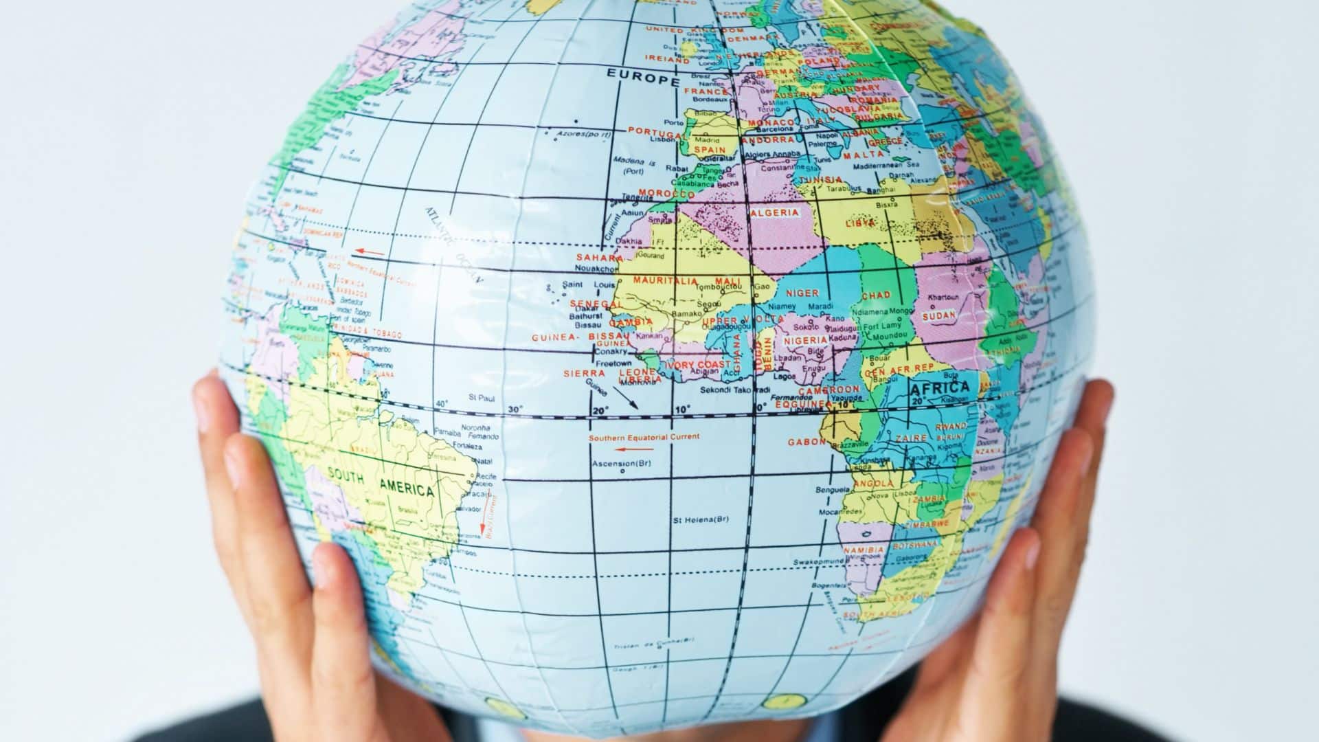 person holding a globe in their hands in front of their face