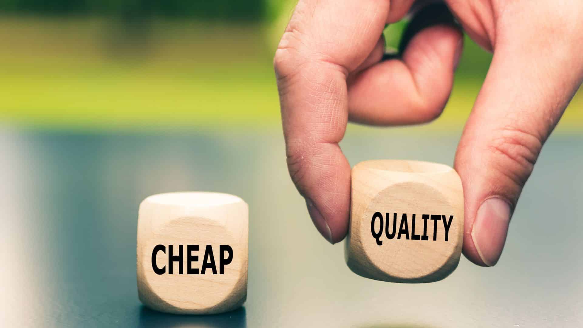 close up of two small dice-sized blocks, one reads "CHEAP" while the other reads "QUALITY" — a man's fingers pinch the "QUALITY" cube and lift it up
