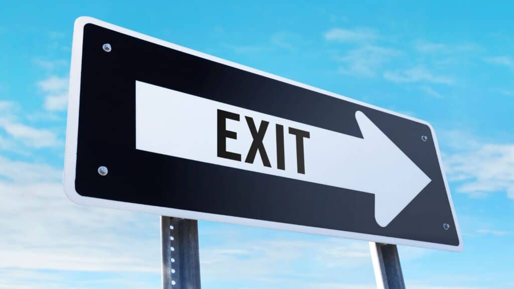 road sign against a blue, slightly cloudy sky; the sign reads "EXIT" with an arrow pointing right