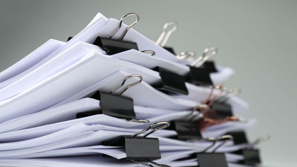 stack of papers, segmented into small bundles with metal binder clips