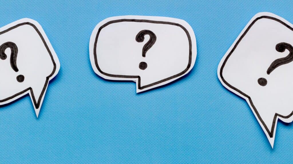 three paper cutouts of speech bubbles with question marks in them laid against a light blue paper background