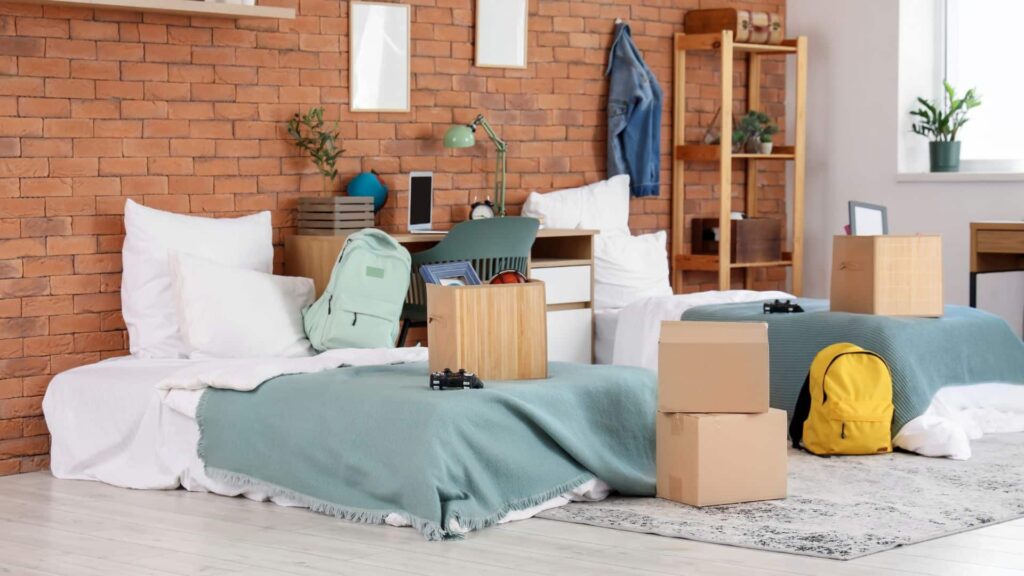 college dorm room with two beds and various moving boxes indicating the occupants are moving in